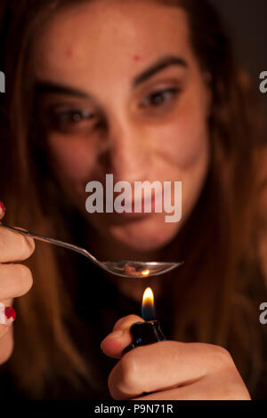 a young drug-addict woman lheated spoon with lighter Stock Photo