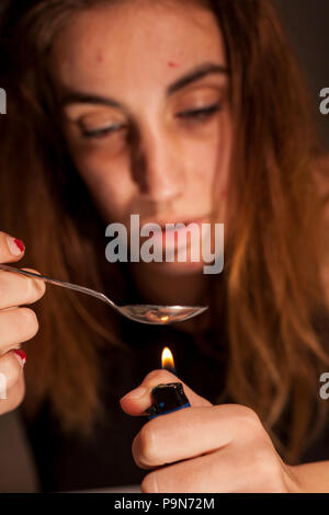 a young drug-addict woman lheated spoon with lighter Stock Photo