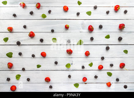 Creative blackberry, Strawberries and leaves colorful pattern on white wooden background. Flat lay. Food concept. Stock Photo