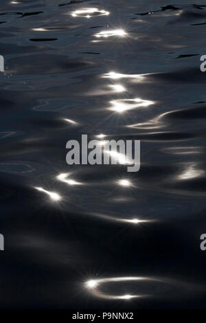 white glare of the sun on a dark dirty surface of water on a lake, close-up photo in autumn Stock Photo