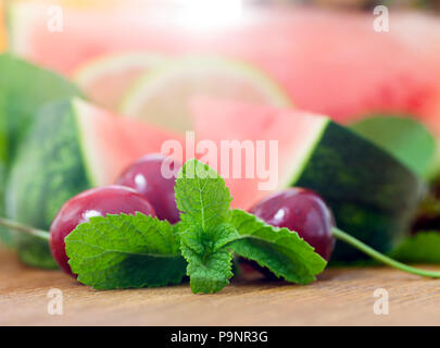lying together an orange, watermelon, pineapple, cherry and mint, cut into pieces during cooking. Photo close-up with little depth of field. Focus on  Stock Photo
