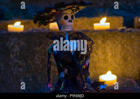 La Calavera Catrina doll at night surrounded by candles for Mexican Day of the Dead Stock Photo