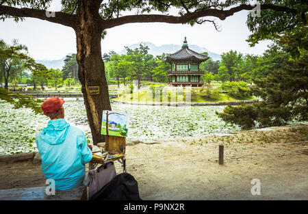 Seoul, Korea - May 11, 2017:  Artist painting Pavilion of the Far-Reaching Fragrance pagoda on an artificial island in the center of a small lake in t Stock Photo