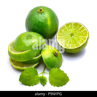 Group of whole limes and sliced halves, lemon balm leaves isolated on white studio background Stock Photo