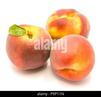 Three whole ripe peaches, one with green leaf, isolated on white background Stock Photo