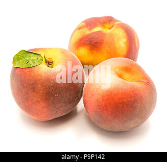 Three whole ripe peaches, one with green leaf, isolated on white background Stock Photo
