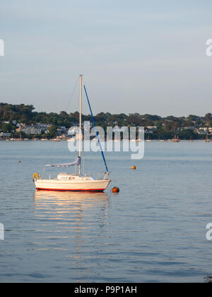 A small sailing boat moored in the River Camel estuary at Padstow Cornwall UK in warm evening sunlight in summer Stock Photo