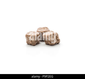 Three coconut cubes in milk chocolate isolated on white background Stock Photo