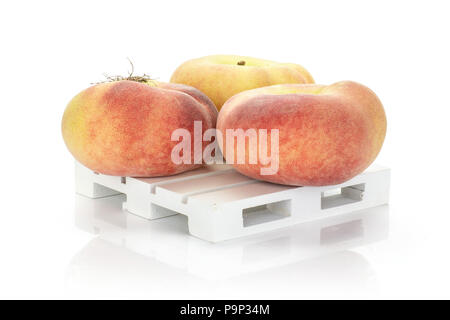 Three fresh ripe Saturn peaches on a wooden pallet isolated on white background Stock Photo