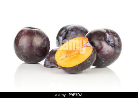 Three red blue plums and two halves isolated on white background Stock Photo