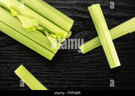 Fresh green celery and three sticks isolated on black wooden background Stock Photo