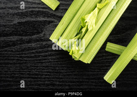 Fresh green celery with three sticks isolated on black wooden background Stock Photo