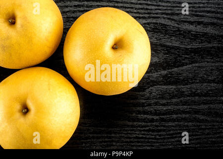 Chinese golden pears top view Nashi variety isolated on black wooden background three whole round Stock Photo