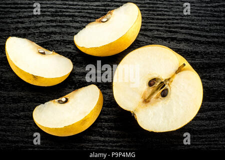 Chinese golden pears top view Nashi variety isolated on black wooden background one cross section half three slices Stock Photo