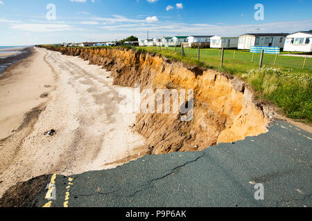 A collapsed coastal road at between Skipsea and Ulrome on Yorkshires East Coast, near Skipsea, UK. The coast is composed of soft boulder clays, very vulnerable to coastal erosion. This section of coast has been eroding since Roman times, with many villages having disappeared into the sea, and is the fastest eroding coast in Europe. Climate change is speeding up the erosion, with sea level rise, increased stormy weather and increased heavy rainfall events, all playing their part. Stock Photo