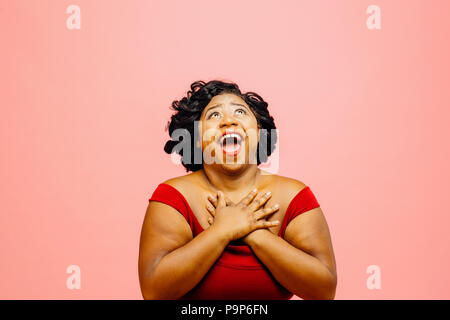 In great awe/Portrait of an extremely excited woman looking up with both hands behind head Stock Photo