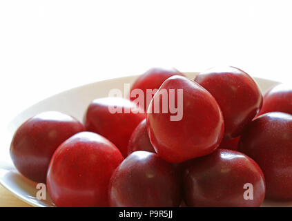 Plate of Fresh Gulf Ruby Plum Fruits in the Morning Light, Selective Focus and Blurred Background Stock Photo