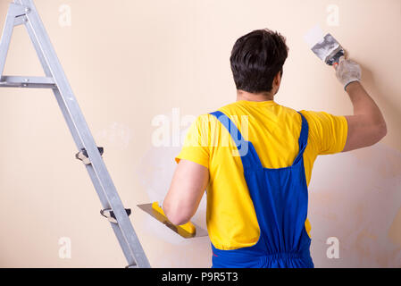 Young contractor employee applying plaster on wall Stock Photo