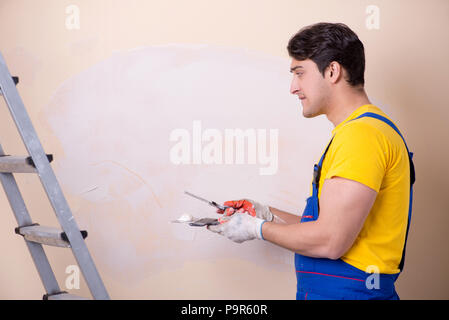Young contractor employee applying plaster on wall Stock Photo