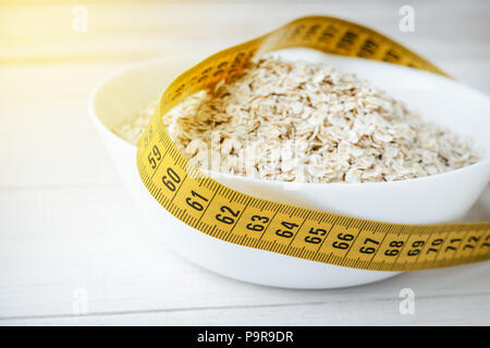 Healthy Breakfast, Sport, Fitness, Diet Concept. A bowl of oatmeal and a measure tape on white background Stock Photo
