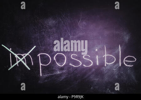 Word impossible transformed into possible on chalkboard. Motivation philosophy concept Stock Photo