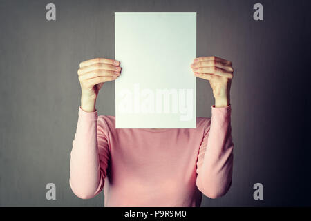 portrait of casual anonymous woman covering face with white paper sheet Stock Photo