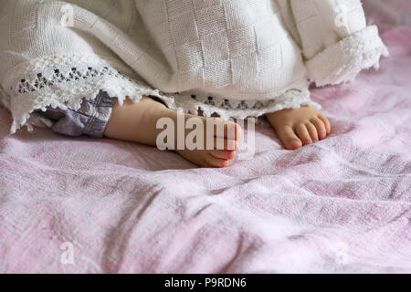 Heel sleeping baby girl sticking out from under the blanket, selective focus Stock Photo