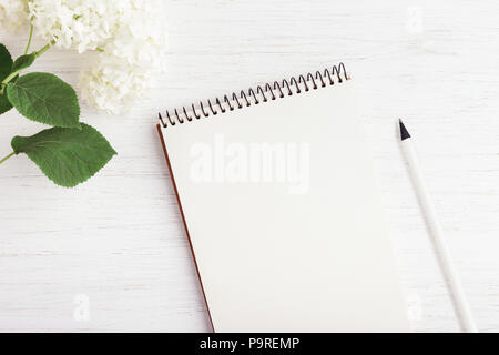 Working place with notebook, pencil and flower on white wooden table. Planning concept, top view. Stock Photo