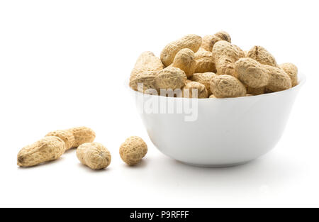 Unshelled raw peanuts in a porcelain bowl isolated on white background some peanuts are out Stock Photo