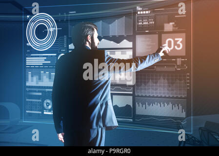 Working at program. Calm creative web developer working at the new useful program and looking elegant in his dark suit Stock Photo