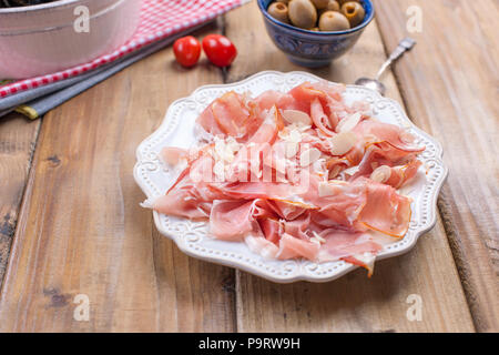 Plate with meat on a wooden background, green olives Stock Photo