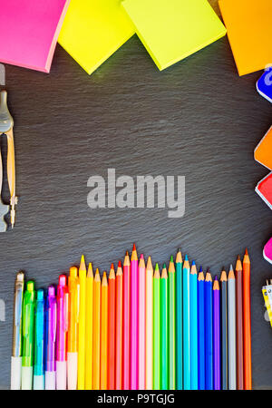 Back to school pencils and notes raibow, copy space on black board, top view, hero header, retro toned Stock Photo