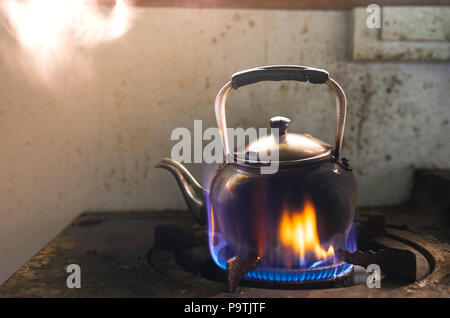 steaming water in Traditional metal kettle on fire on gas stove in kitchen Stock Photo