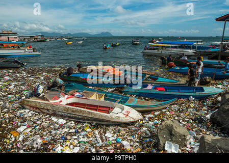 Plastic pollution floating next to small boats at the waterfront in Semporna town in Sabah, (Malaysian Borneo), Malaysia. Stock Photo