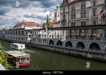 Slovenia, Europe: he skyline of downtown Ljubljana with a tourist boat cruising on the Ljubljanica river, known in the Middle Ages as the Ljubija Stock Photo