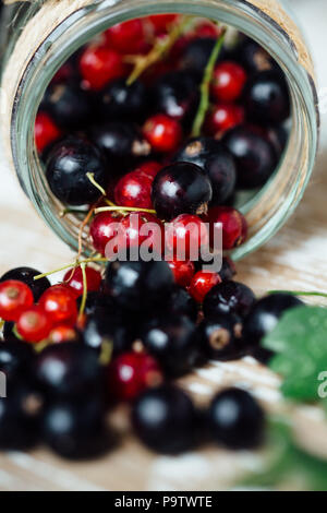 Fresh ripe red and black currants on the background of a wooden table. Wooden background Stock Photo
