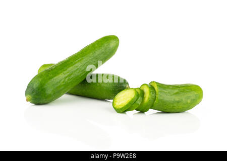 Two fresh green mini cucumbers and sliced half with three slices isolated on white background Stock Photo