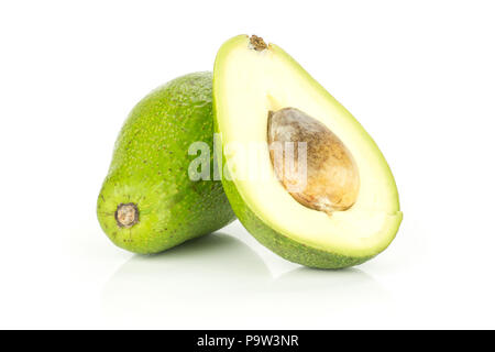 Green smooth avocado and one sliced half with a brown seed isolated on white background bacon variety Stock Photo