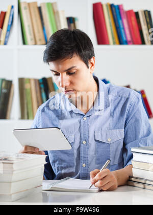 Student learning in library, using digital tablet Stock Photo