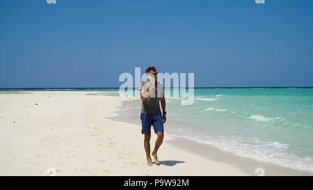 Man talking on the mobile phone at the beach. Man talking on cell phone and walking along beach. Beach, sea, sand,wave. Philippines, Travel concept. Stock Photo