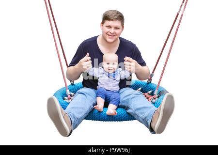 Father with son sitting on big modern chain swing and laughing. Parent with baby boy enjoying swinging on seesaw at playground. Happy childhood and pa Stock Photo