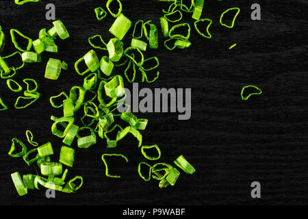 Fresh green spring onion red scallion variety chopped pieces flatlay on black wood Stock Photo
