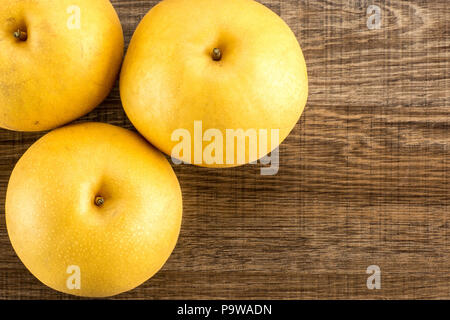Chinese golden pears top view Nashi variety isolated on wooden background three whole round Stock Photo