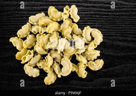 Pasta creste di gallo flatlay spinach raw isolated on black wood background top view Stock Photo