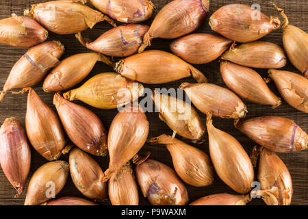 Shallots long onions flatlay isolated on brown wood background Stock Photo
