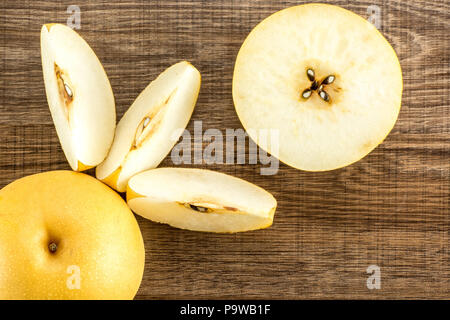 Chinese golden pears top view Nashi variety isolated on wooden background one round whole cross section half and three slices Stock Photo