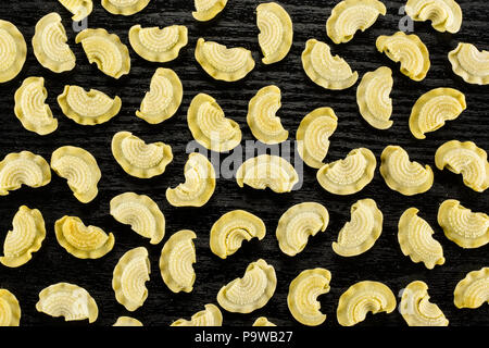 Pasta raw creste di gallo flatlay isolated on black wood background top view spinach Stock Photo