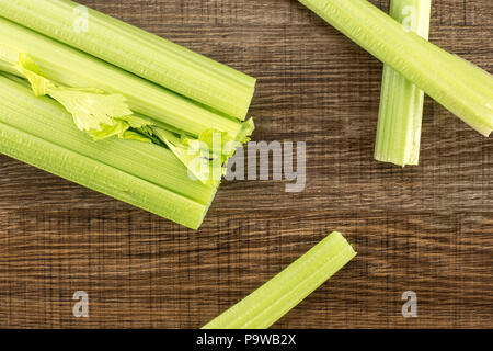 One fresh green celery with three sticks isolated on wooden background Stock Photo