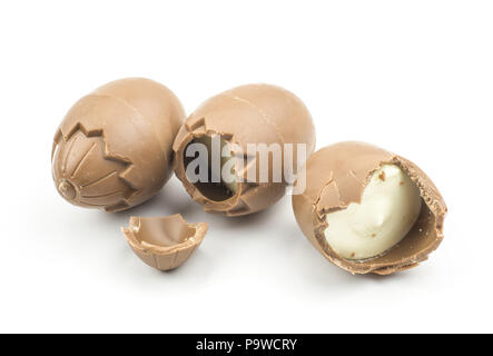 Three chocolate eggs one cracked and one half isolated on white background Stock Photo