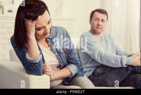 Feeling desperate. Cheerless unhappy pleasant woman holding her forehead and thinking about problems with her husband while feeling desperate Stock Photo